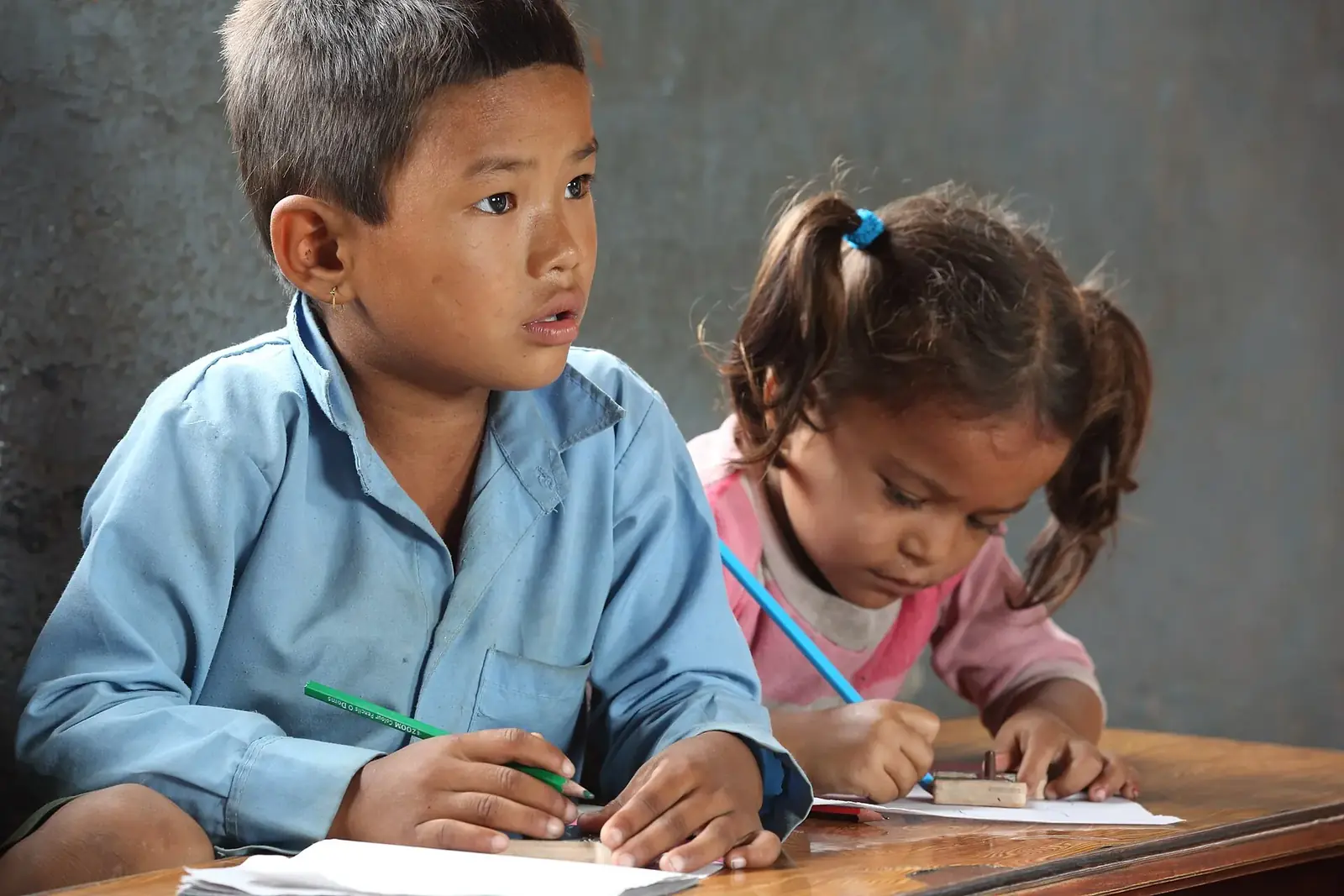 Two young children writing in the playgroup class at Shree Sahara Bal Primary School, Pokhara